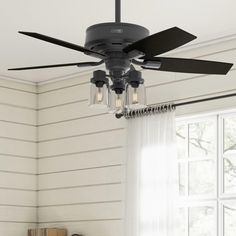 a ceiling fan with three lights hanging from it's blades in front of a window