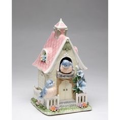 a figurine of a bird house with two birds on the roof and flowers around it
