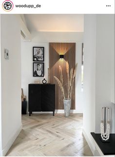 a room with white walls and wood flooring next to a black cabinet in the corner