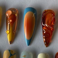 six different colored glass objects are lined up on a white surface, one is orange and the other is blue