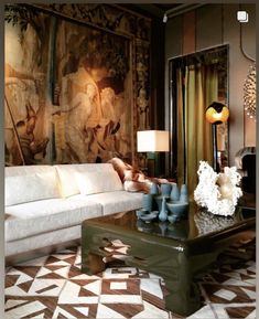 a living room filled with furniture next to a painting on the wall above a coffee table