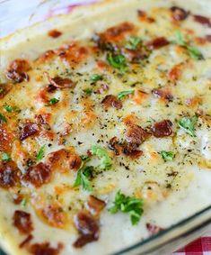 a casserole dish with cheese, bacon and parsley in it on a checkered table cloth