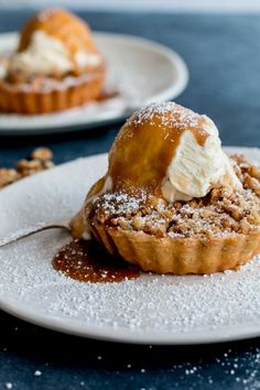 two small desserts on plates with powdered sugar and icing, sitting on a table