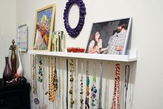 there is a white shelf with many necklaces on it and pictures hanging from the wall