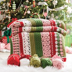 a christmas tree is in the background with crocheted blankets and balls of yarn