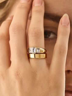 a close up of a person wearing a gold ring with three stones on the side