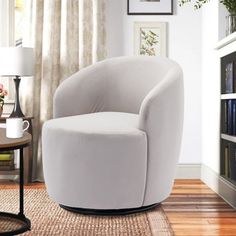 a white chair sitting on top of a hard wood floor next to a book shelf