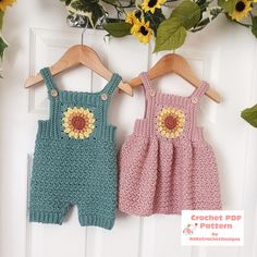 two crochet baby rompers hanging on a door with sunflowers in the background