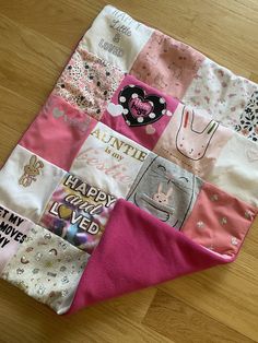 a pink and white patchwork quilt on top of a wooden floor