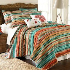 a bed with colorful bedspreads and pillows