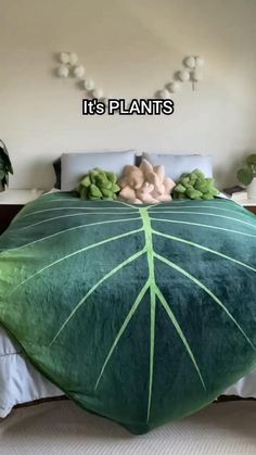 a large green leaf shaped pillow sitting on top of a bed next to two pillows