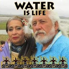 a man and woman standing next to each other in front of a sign that says water is life