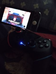 a person holding a video game controller in front of a cell phone that is turned on
