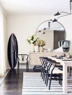 a dining room table with black chairs and a round mirror on the wall above it