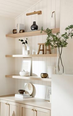 the shelves are filled with vases, books and other decorative items in white painted wood