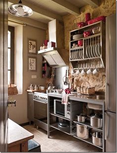 a kitchen with lots of pots and pans on the shelves above the stove top