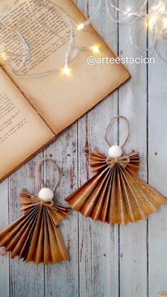 an open book and some paper fans on a wooden table with string lights in the background