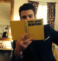 a man in a suit holding up a book with the title still more bones written on it