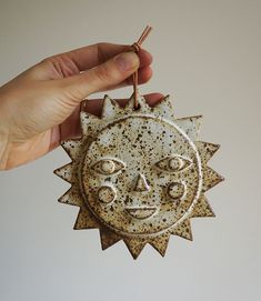 a hand holding a small ceramic sun ornament