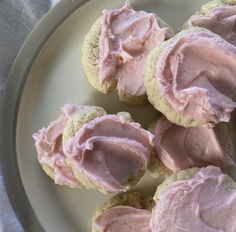 some pink frosted cookies on a white plate