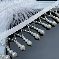 a white feather and some pearls on a table