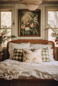 a bed with white sheets and pillows in front of two large paintings on the wall