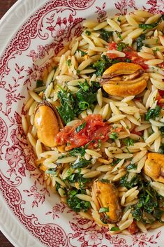 pasta with spinach and tomatoes in a red and white bowl
