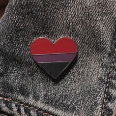 a red, white and blue heart shaped pin sitting on the back of a pair of jeans