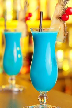 two blue cocktails sitting on top of a wooden table