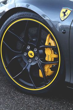 the front wheel of a sports car with yellow rims and brake pads on it