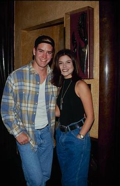 a man and woman standing next to each other in front of a wall mounted clock