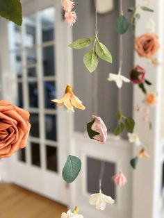 some flowers are hanging from a string in a room with white walls and wooden floors