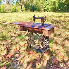 an old sewing machine sitting on top of a wooden table in the middle of a field