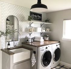a washer and dryer in a room with white tiles on the walls, black accents