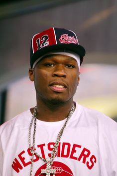 a close up of a person wearing a baseball cap and chain around his neck,