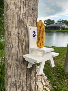 a corn on the cob sitting on top of a white chair next to a tree