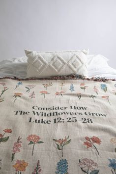 the comforter has flowers on it and is next to a pillow that says consider low, the wallflowers grow luke 12 25 28