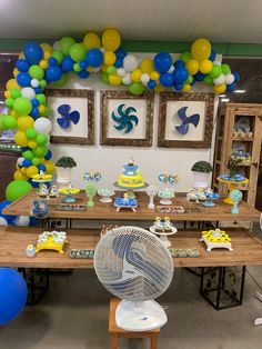 a table with balloons and decorations for a children's birthday party in blue, green, yellow and white