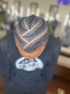 a man with a black shirt and some braids on his head is looking down at the floor