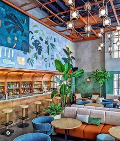 the inside of a restaurant with blue and orange chairs, tables, and potted plants