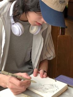 a woman with headphones on writing in a book while wearing earbud's