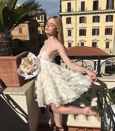 a woman in a white dress standing on a balcony