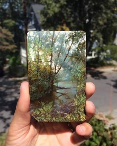 a person holding up an image of a river in the woods