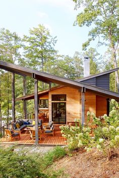 a wooden house surrounded by greenery and trees on a sunny day in the woods