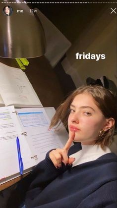 a woman sitting at a desk with a notebook and pen in her hand