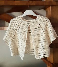 a white crocheted sweater hanging on a hanger