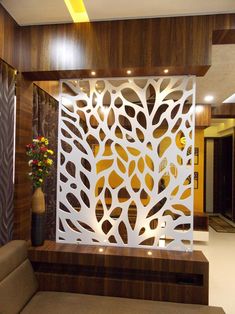 a living room area with a couch and decorative wall panel in the center, along with a vase filled with flowers