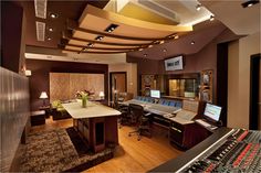 a recording studio with many equipment in the room and lights on above the sound board