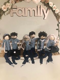 a group of dolls sitting on top of a wooden bench next to a family sign