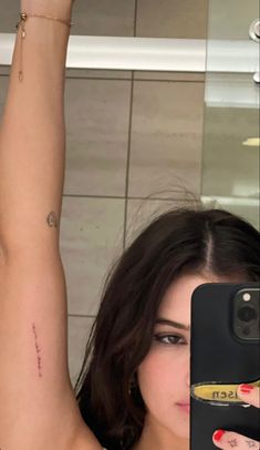 a woman is taking a selfie in the mirror with her cell phone and tattoo on her arm